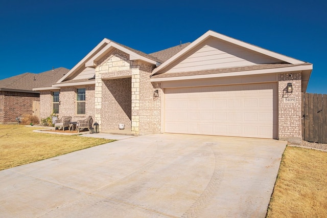 view of front of property featuring brick siding, an attached garage, a front yard, fence, and driveway