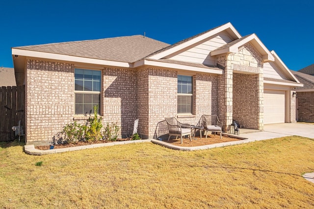 view of front facade with a garage, driveway, fence, a front lawn, and brick siding