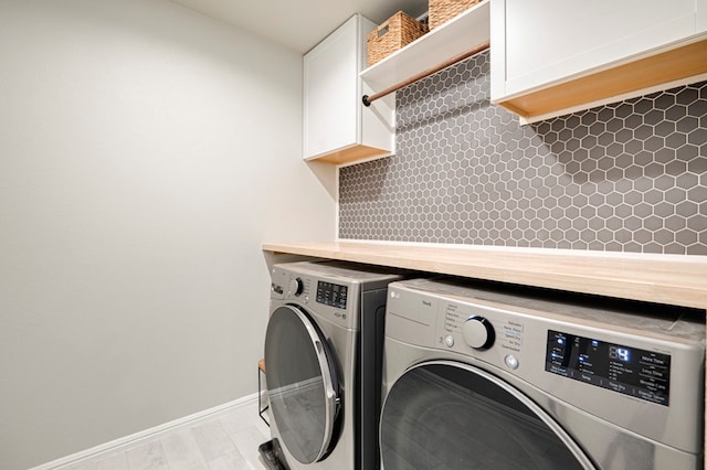 laundry room with washing machine and clothes dryer, cabinet space, and baseboards