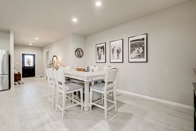 dining room featuring baseboards, light wood finished floors, and recessed lighting