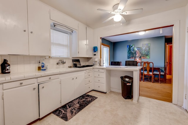 kitchen featuring backsplash, tile countertops, white cabinets, and a healthy amount of sunlight