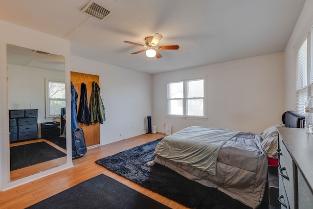 bedroom with ceiling fan, light hardwood / wood-style flooring, and multiple windows