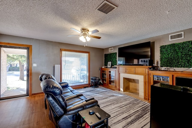 living room with hardwood / wood-style floors, ceiling fan, a textured ceiling, and a wealth of natural light