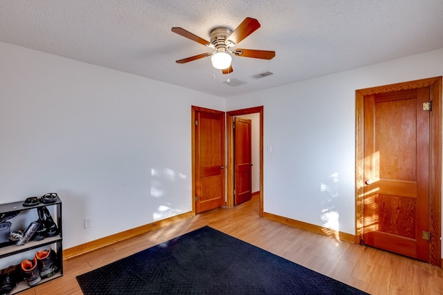 bedroom featuring ceiling fan, light wood-type flooring, and a textured ceiling