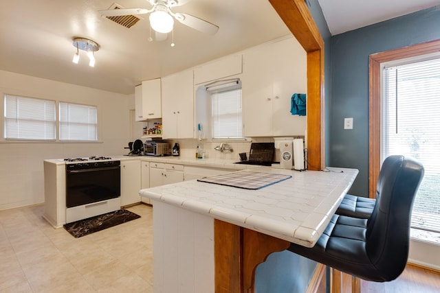 kitchen with tile countertops, white cabinetry, plenty of natural light, and white range