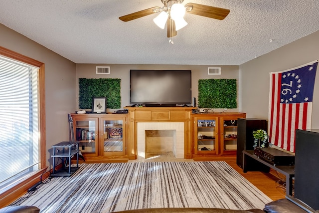 living room with ceiling fan, a textured ceiling, and hardwood / wood-style flooring