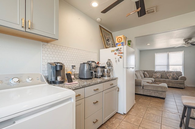 kitchen featuring washer / dryer, visible vents, ceiling fan, freestanding refrigerator, and backsplash