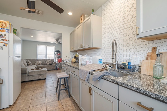 kitchen with ceiling fan, open floor plan, freestanding refrigerator, and decorative backsplash