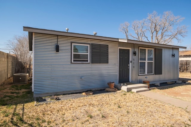 view of front of property with entry steps, fence private yard, and central air condition unit