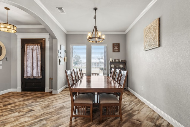 dining space with ornamental molding, visible vents, baseboards, and wood finished floors