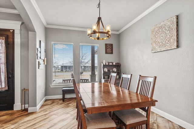 dining room with light wood-type flooring, an inviting chandelier, baseboards, and crown molding