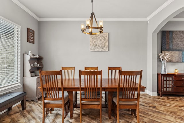 dining room with arched walkways, crown molding, a notable chandelier, wood finished floors, and baseboards