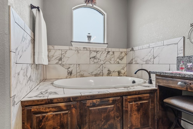 full bath with a garden tub, vanity, and a textured wall