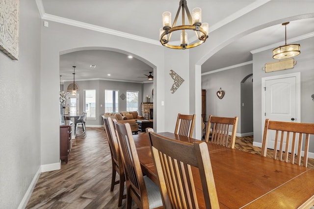 dining room featuring crown molding, a fireplace, arched walkways, and dark wood-type flooring