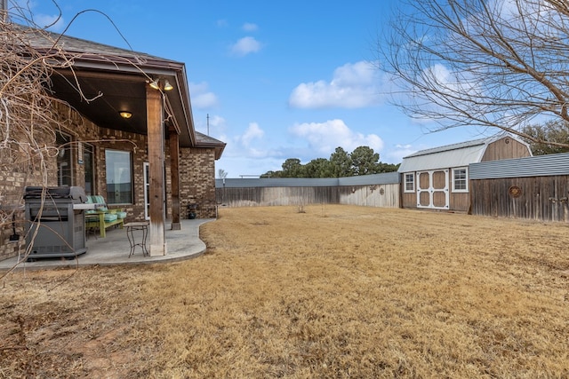 view of yard with fence, a storage unit, a patio, and an outbuilding