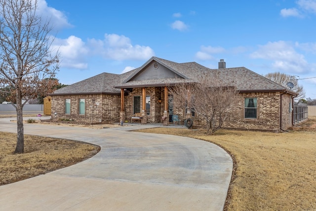 ranch-style house with brick siding, curved driveway, a chimney, roof with shingles, and fence