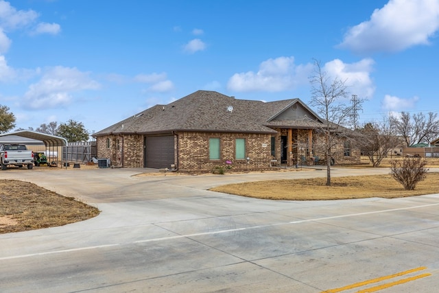 single story home featuring a garage, concrete driveway, roof with shingles, a carport, and brick siding