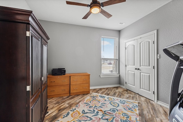 interior space featuring ceiling fan, wood finished floors, visible vents, and baseboards