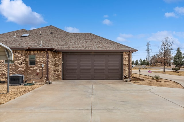 view of side of property featuring central AC unit, an attached garage, brick siding, driveway, and roof with shingles