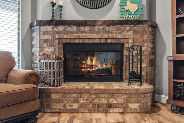 room details featuring a textured wall, a fireplace, wood finished floors, and baseboards