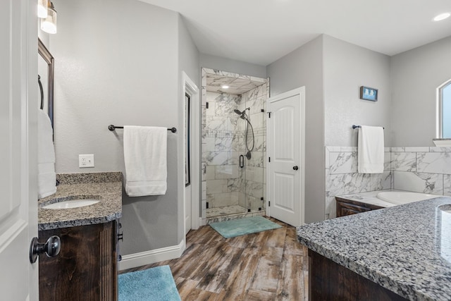 full bath featuring a garden tub, vanity, a shower stall, wood finished floors, and baseboards