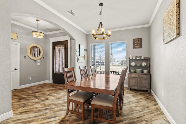 dining space with arched walkways, visible vents, baseboards, and wood finished floors