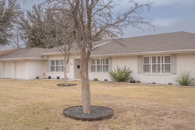 ranch-style house featuring a front yard, brick siding, and roof with shingles