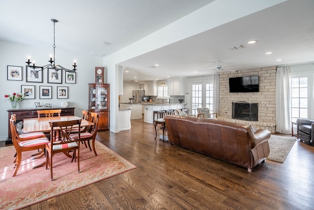 living room featuring visible vents, dark wood-type flooring, ceiling fan with notable chandelier, a fireplace, and recessed lighting