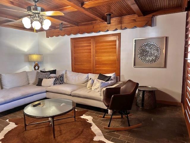 living room with beamed ceiling, wooden ceiling, and ceiling fan