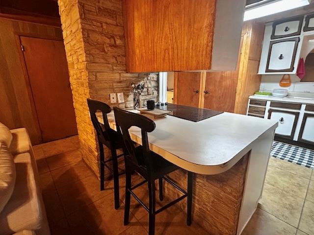 kitchen with tile patterned floors, kitchen peninsula, and a breakfast bar