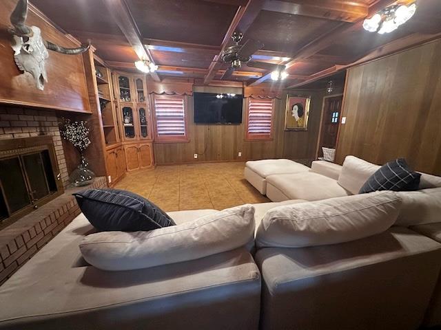 home theater with coffered ceiling, wooden walls, a brick fireplace, and light tile patterned floors