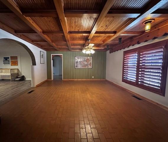 empty room with ceiling fan, wood ceiling, and beamed ceiling