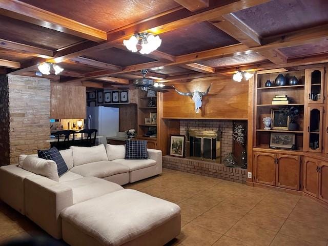 living room featuring coffered ceiling, a brick fireplace, light tile patterned floors, and beam ceiling