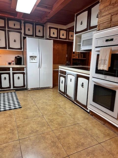 kitchen with coffered ceiling, white appliances, beam ceiling, and light tile patterned floors