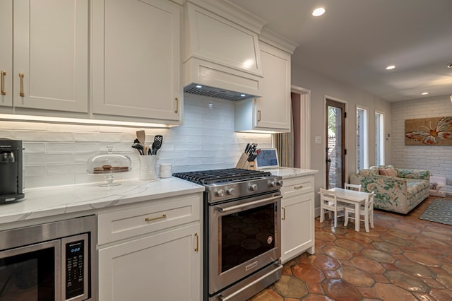 kitchen featuring light stone countertops, decorative backsplash, white cabinetry, and stainless steel appliances