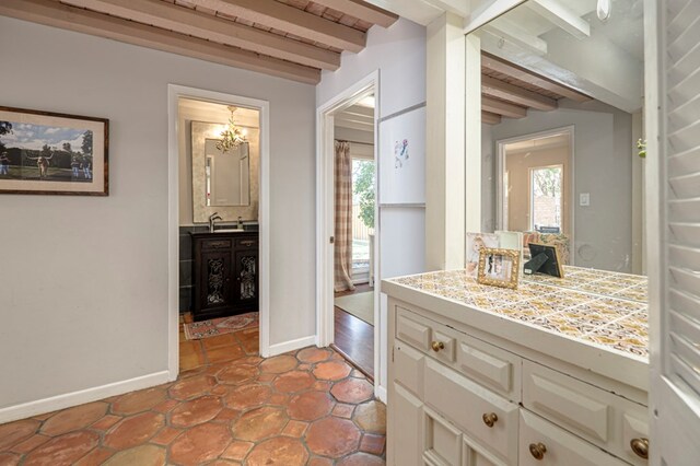 bathroom with beamed ceiling, vanity, and a chandelier