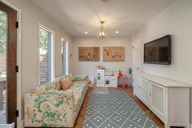 living room featuring dark hardwood / wood-style floors, an inviting chandelier, and brick wall