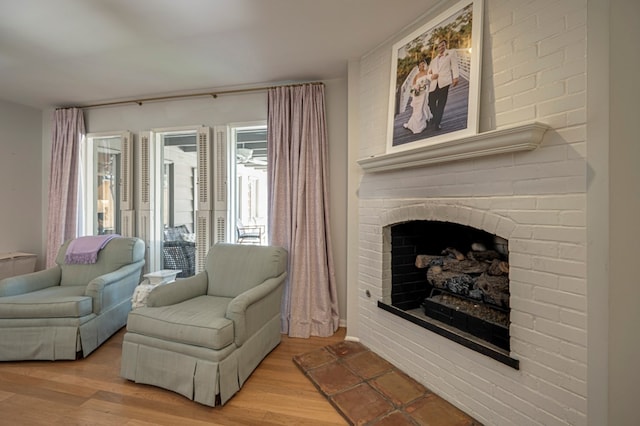 living area with a brick fireplace and light hardwood / wood-style flooring