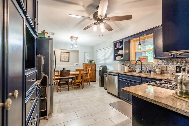 kitchen featuring appliances with stainless steel finishes, a sink, decorative backsplash, ceiling fan, and decorative light fixtures