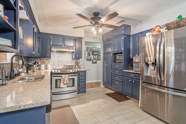 kitchen with appliances with stainless steel finishes, a sink, blue cabinets, a ceiling fan, and decorative backsplash