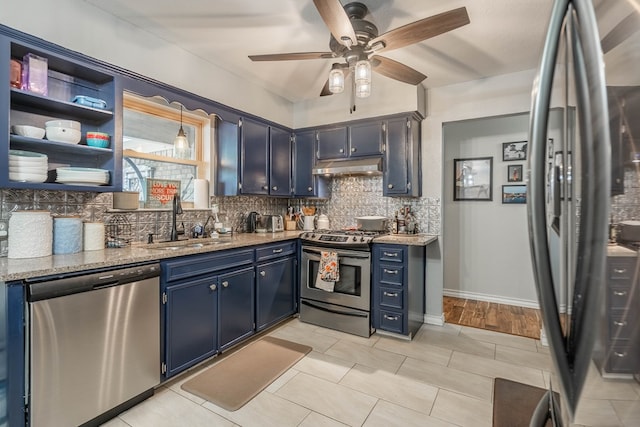 kitchen with stainless steel appliances, a sink, under cabinet range hood, blue cabinets, and decorative backsplash