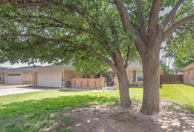 view of property hidden behind natural elements featuring brick siding, a garage, and driveway