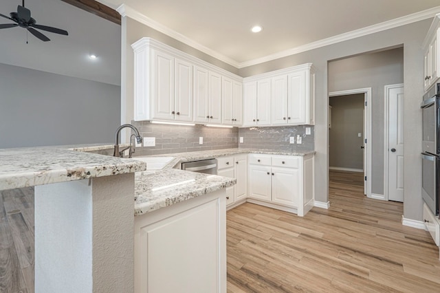 kitchen with dishwasher, sink, white cabinets, kitchen peninsula, and light stone countertops