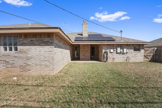 4910 Rio Grande Ave, Midland, TX 79707 - back of house featuring roof mounted solar panels, a patio, a chimney, and brick siding