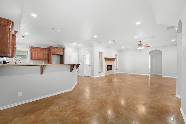 4910 Rio Grande Ave, Midland, TX 79707 - unfurnished living room with arched walkways, ceiling fan, recessed lighting, and a tile fireplace