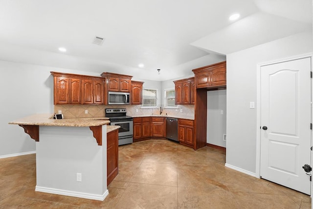 4910 Rio Grande Ave, Midland, TX 79707 - kitchen with stainless steel appliances, a breakfast bar, backsplash, recessed lighting, and light stone counters