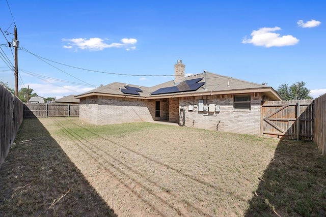4910 Rio Grande Ave, Midland, TX 79707 - back of house featuring brick siding, solar panels, a fenced backyard, and a chimney