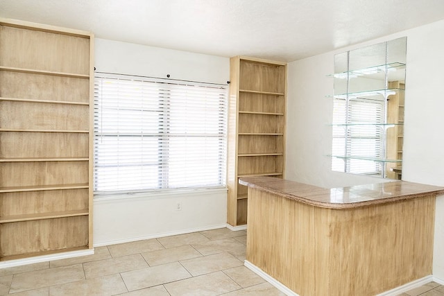 unfurnished office with a bar, plenty of natural light, light tile patterned flooring, and baseboards