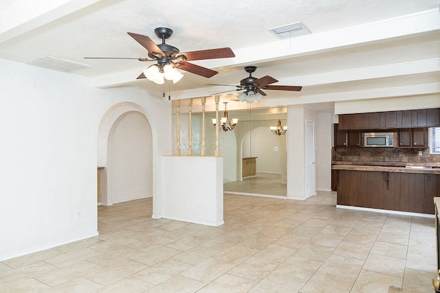unfurnished living room featuring arched walkways, a chandelier, ceiling fan, baseboards, and light tile patterned floors