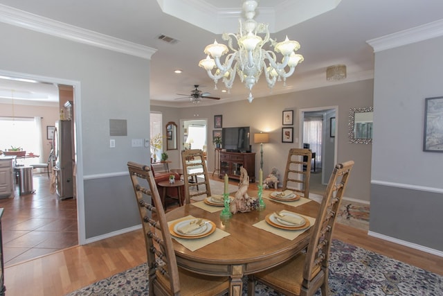 dining area featuring baseboards, wood finished floors, visible vents, and crown molding